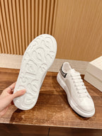 White sneaker outsole and side profile with black rhinestone heel tab