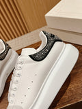 White leather sneaker with black jeweled strap across the collar