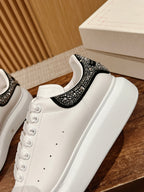 White leather sneaker with black jeweled strap across the collar