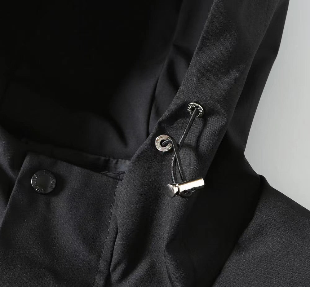 Black coat detail with cord toggle and button on the hood area