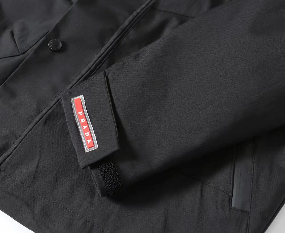 Black fabric coat with Prada logo label on chest pocket