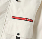 Prada chest label on white long jacket with red stripe and snap button detail