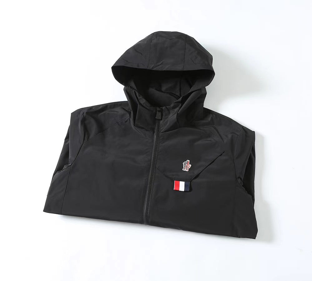 Moncler long black hooded jacket laid flat, chest logo and front zipper