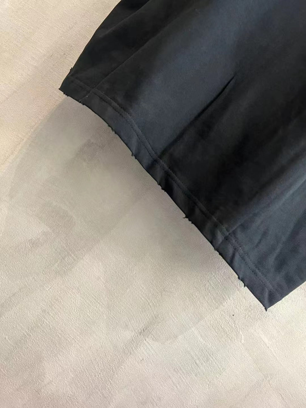 Black T-shirt sleeve and hem with visible stitching detail