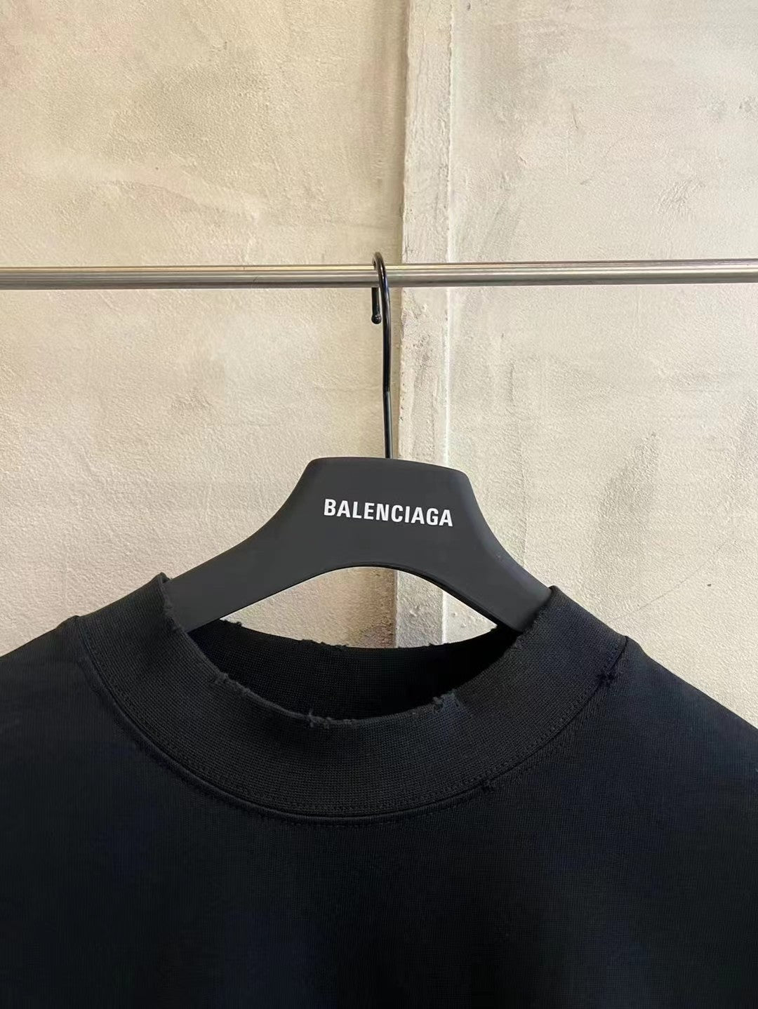 Black crew-neck T-shirt with neckline seam and hanging neck label