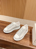 Pair of white lace-up sneakers with ribbed side panel stripes and white soles