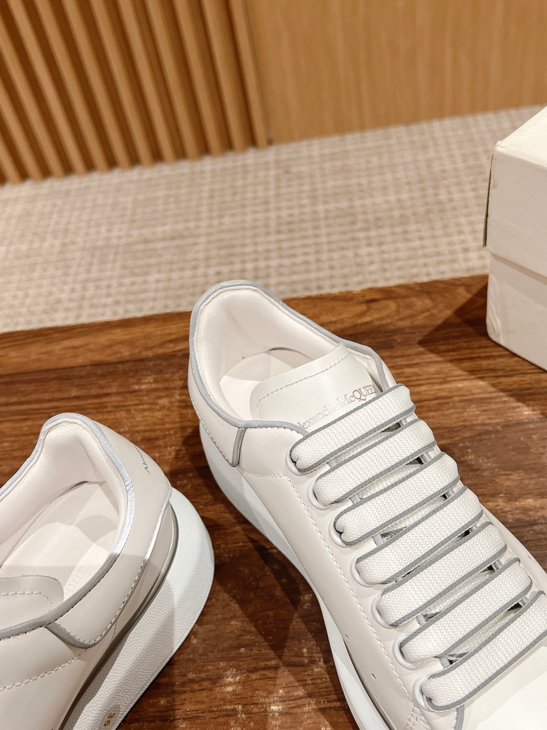 White leather sneakers close-up showing lace-up tongue and side panel stripes