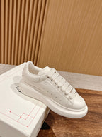 White leather low-top sneakers with lace-up front and smooth rubber sole