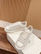 White leather lace-up sneakers with textured panels and low-profile sole