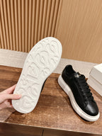 White outsole view of black lace-up sneakers with textured tread