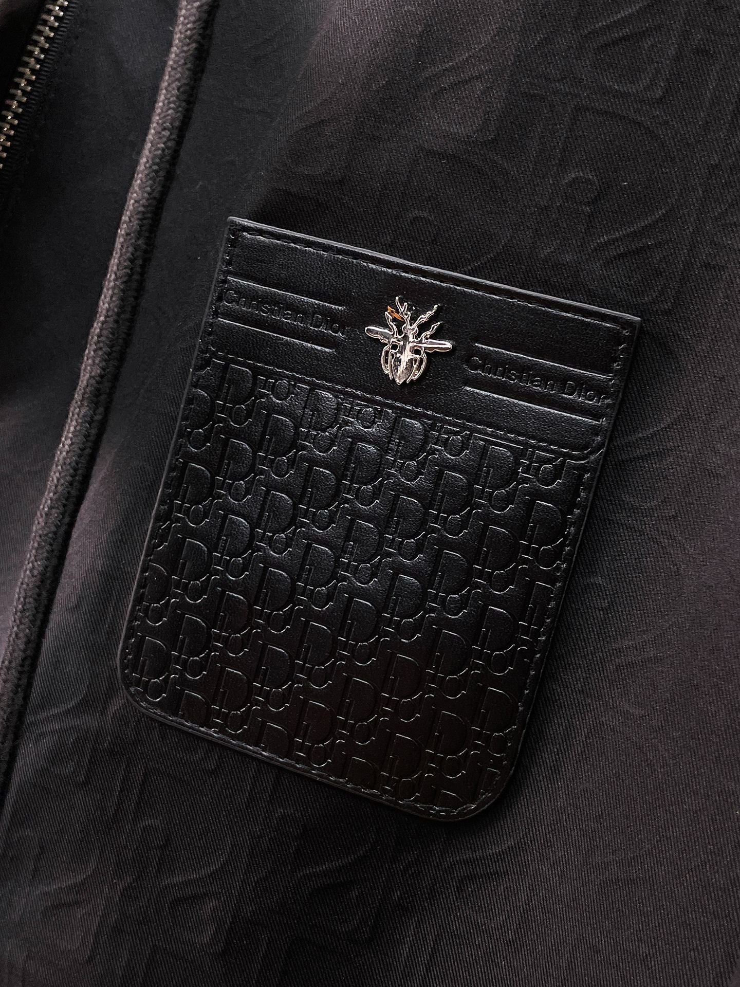 Dior long jacket, close-up of black embossed logo pocket with flap and snap