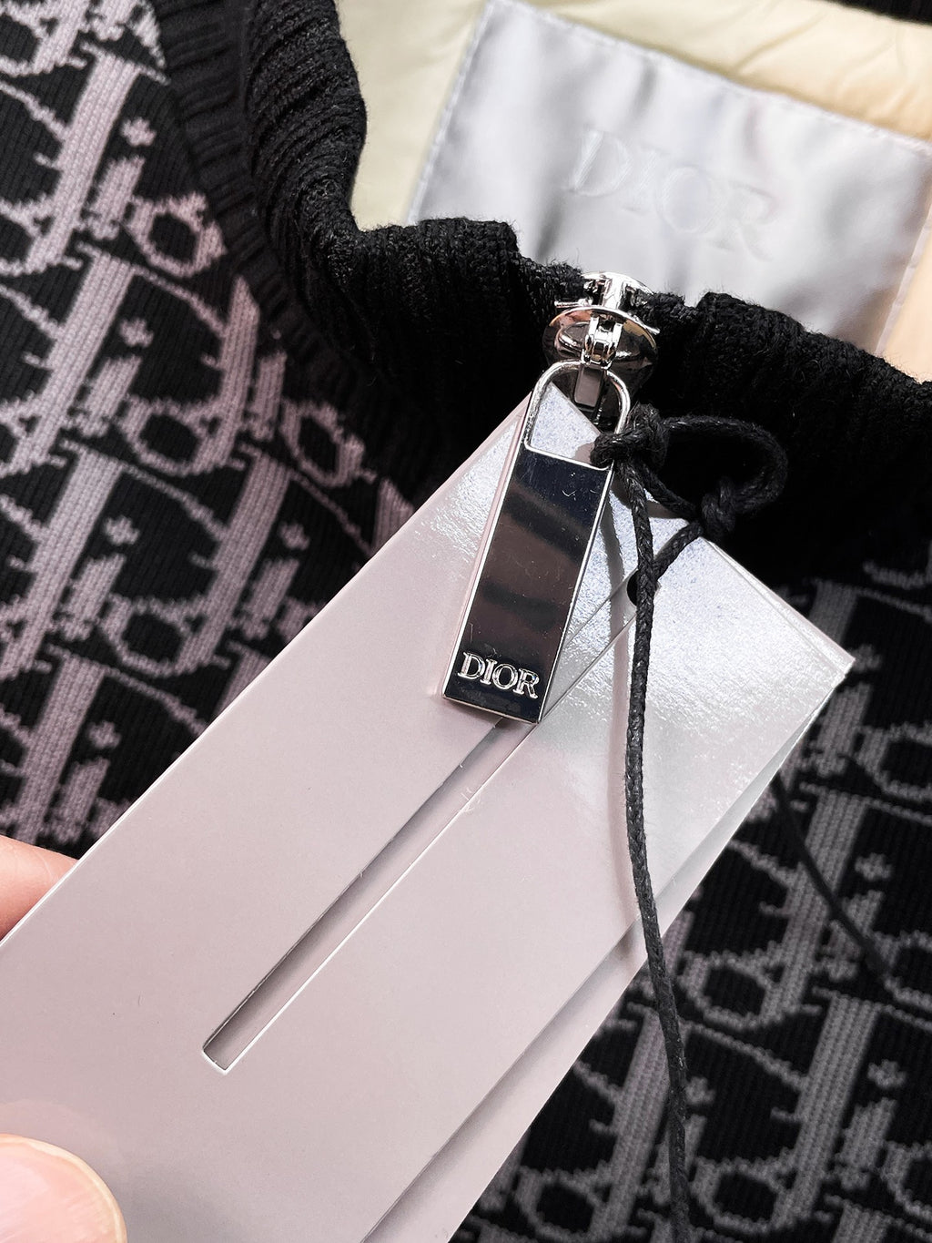 Dior logo hang tag attached to black monogram vest with zipper pull