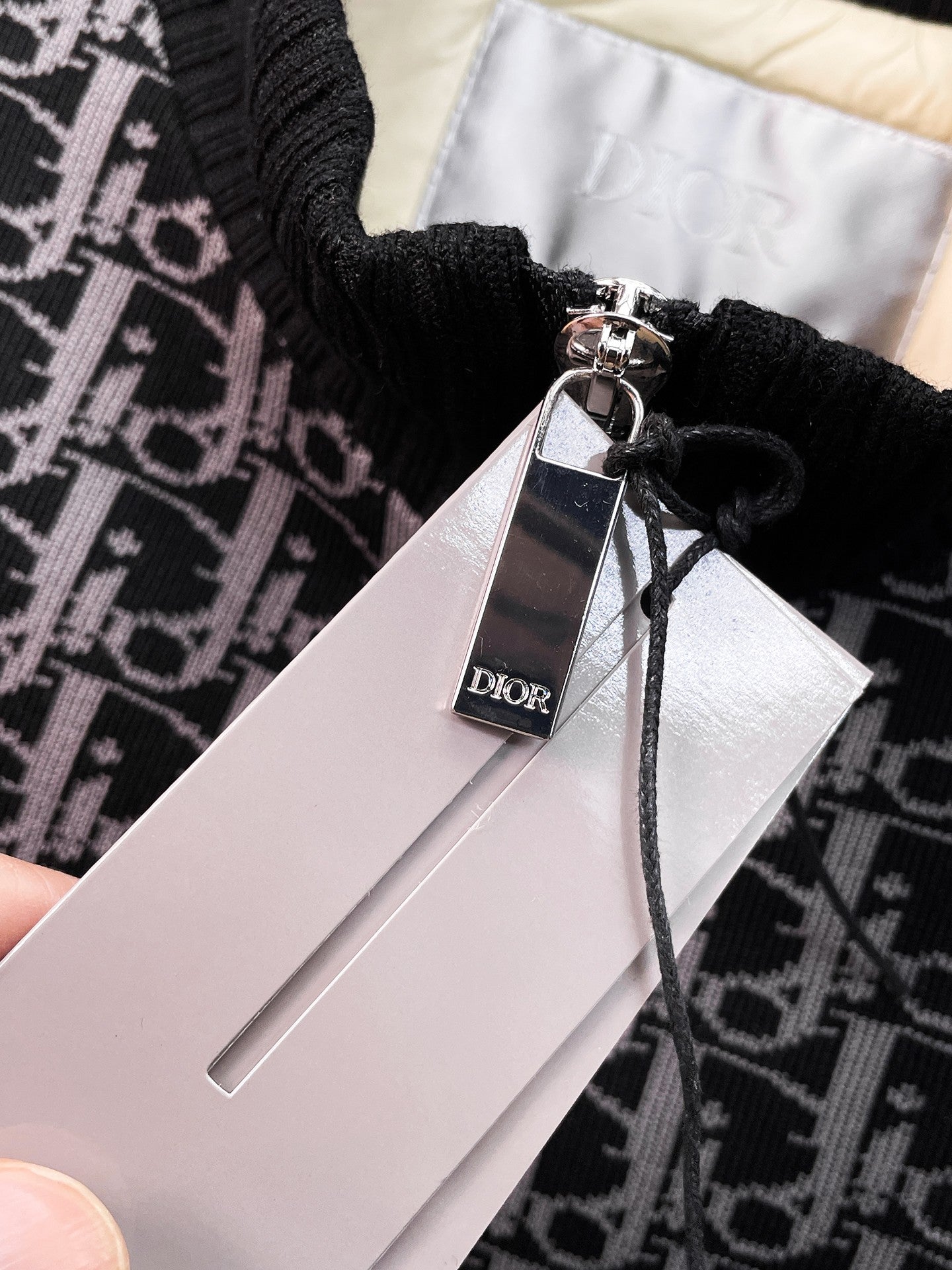 Dior logo hang tag attached to black monogram vest with zipper pull