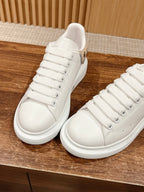 Two white lace-up sneakers showing side profile and padded tongue, Alexander McQueen
