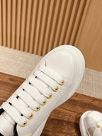Close-up of white low-top sneaker with gold eyelets and white laces