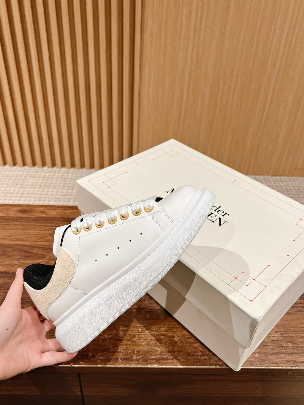 White leather low-top sneakers with black collar and gold eyelets