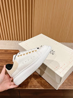 White leather low-top sneakers with black collar and gold eyelets