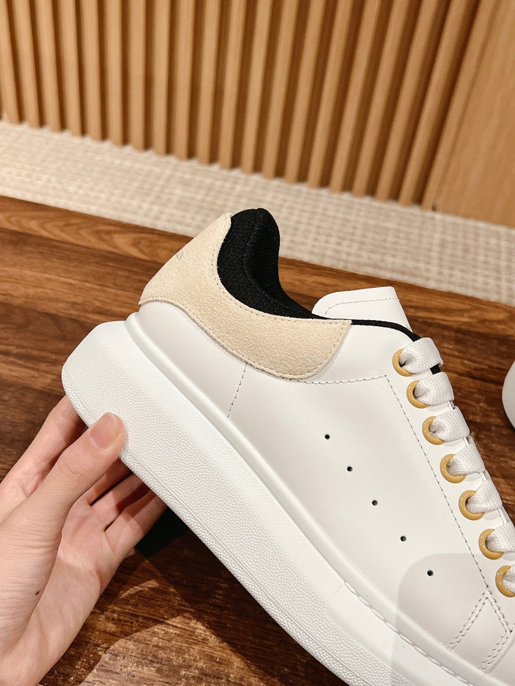 White low-top lace-up sneaker with black collar lining and gold eyelets