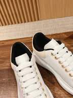 White leather low-top sneakers with black lining and gold eyelets
