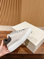 White low-top sneakers with gray panels, black heel, lace-up design