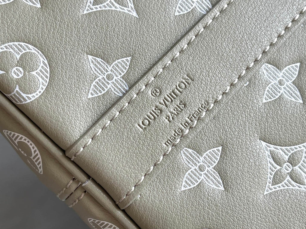 Louis Vuitton duffel bag beige leather panel with embossed logo text and monogram pattern