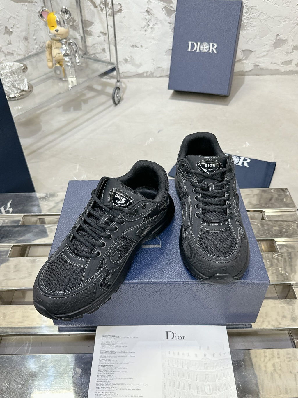 Charcoal gray lace-up sneakers with stitched panel detailing, on a blue box