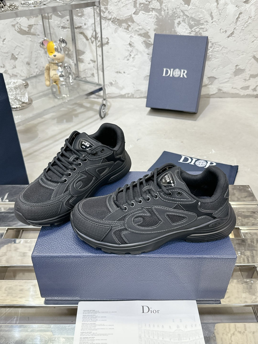Pair of charcoal gray lace-up sneakers on blue box, side-by-side
