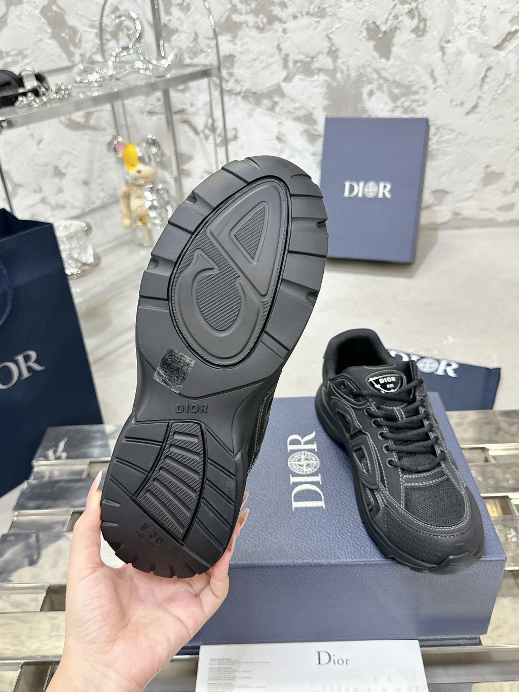 Charcoal gray sneaker outsole with tread pattern, held above a blue box