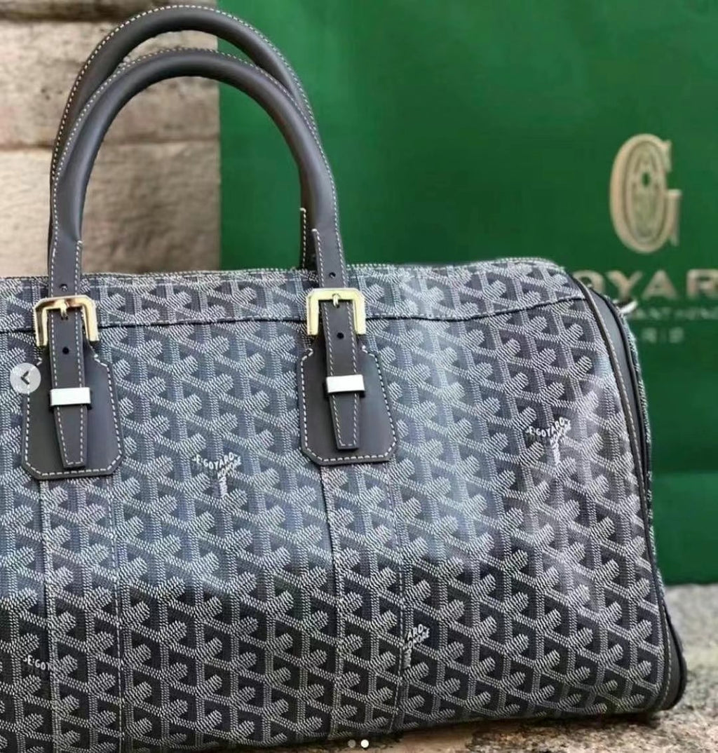 Goyard bag with dark blue patterned canvas, black leather trim, and top handles