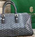 Goyard bag with dark blue patterned canvas, black leather trim, and top handles