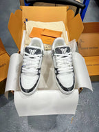 Two-tone Louis Vuitton trainer shoes with gray monogram sides, white laces, lace-up profile.