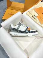 White and dark monogram Louis Vuitton trainer shoes on light paper, lace-up front.