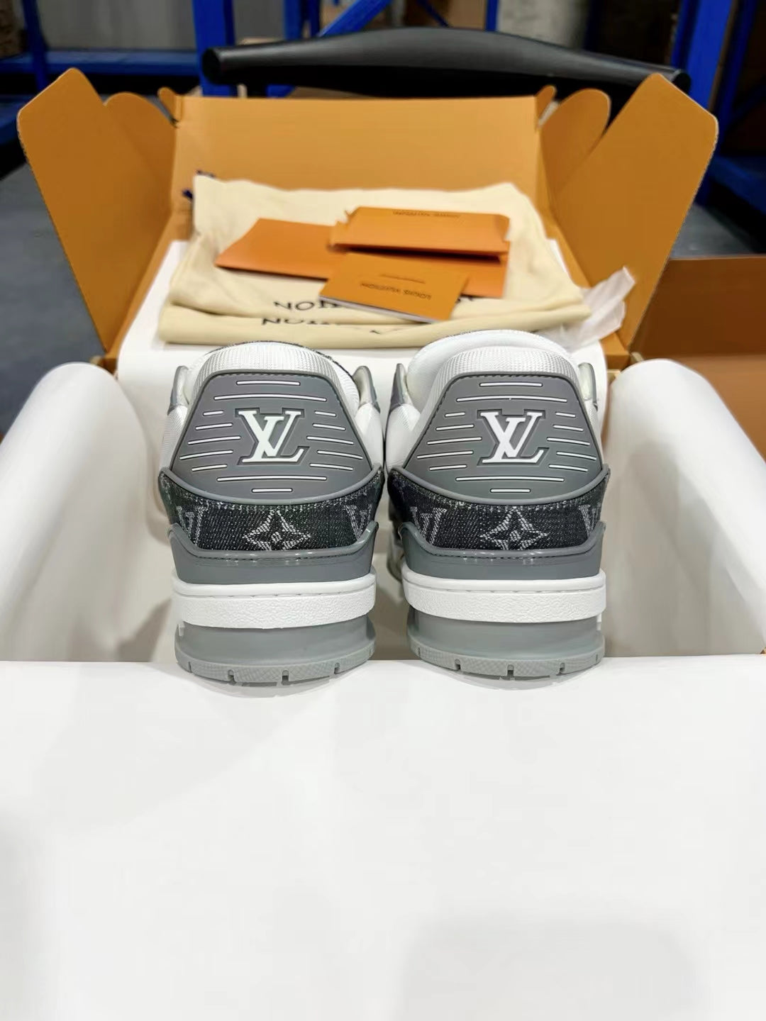 Back view of Louis Vuitton trainer shoes with dark monogram heels and white rubber soles.