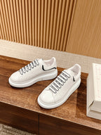 Pair of white lace-up sneakers with black side stripe and round toe