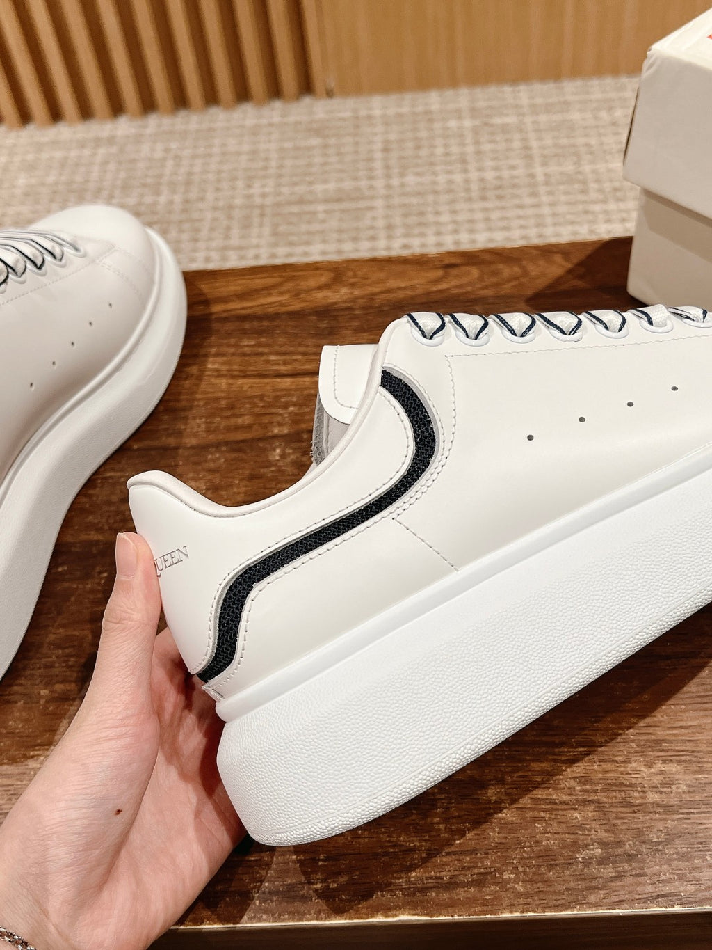 White sneaker side view with black collar stripe and textured sole