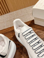 Close-up of white lace-up sneaker with black side stripe and stitched toe