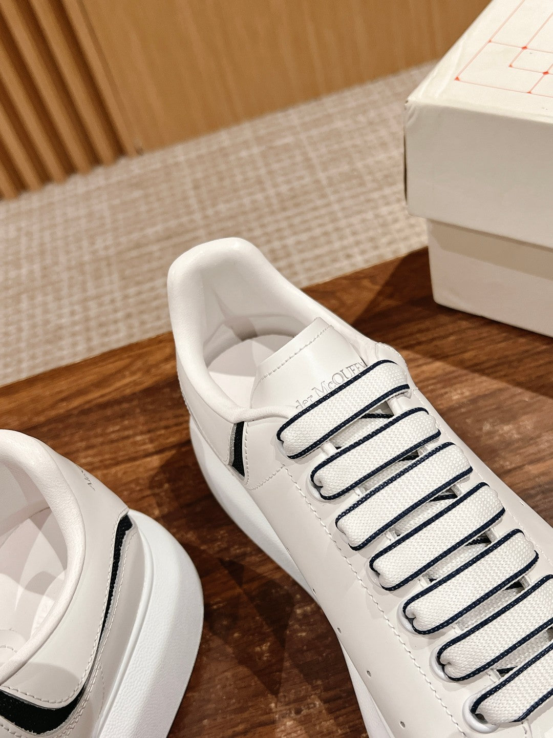 Close-up of white lace-up sneaker with black side stripe and stitched toe