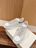 White leather lace-up sneakers on box, featuring perforated toe and contrast piping