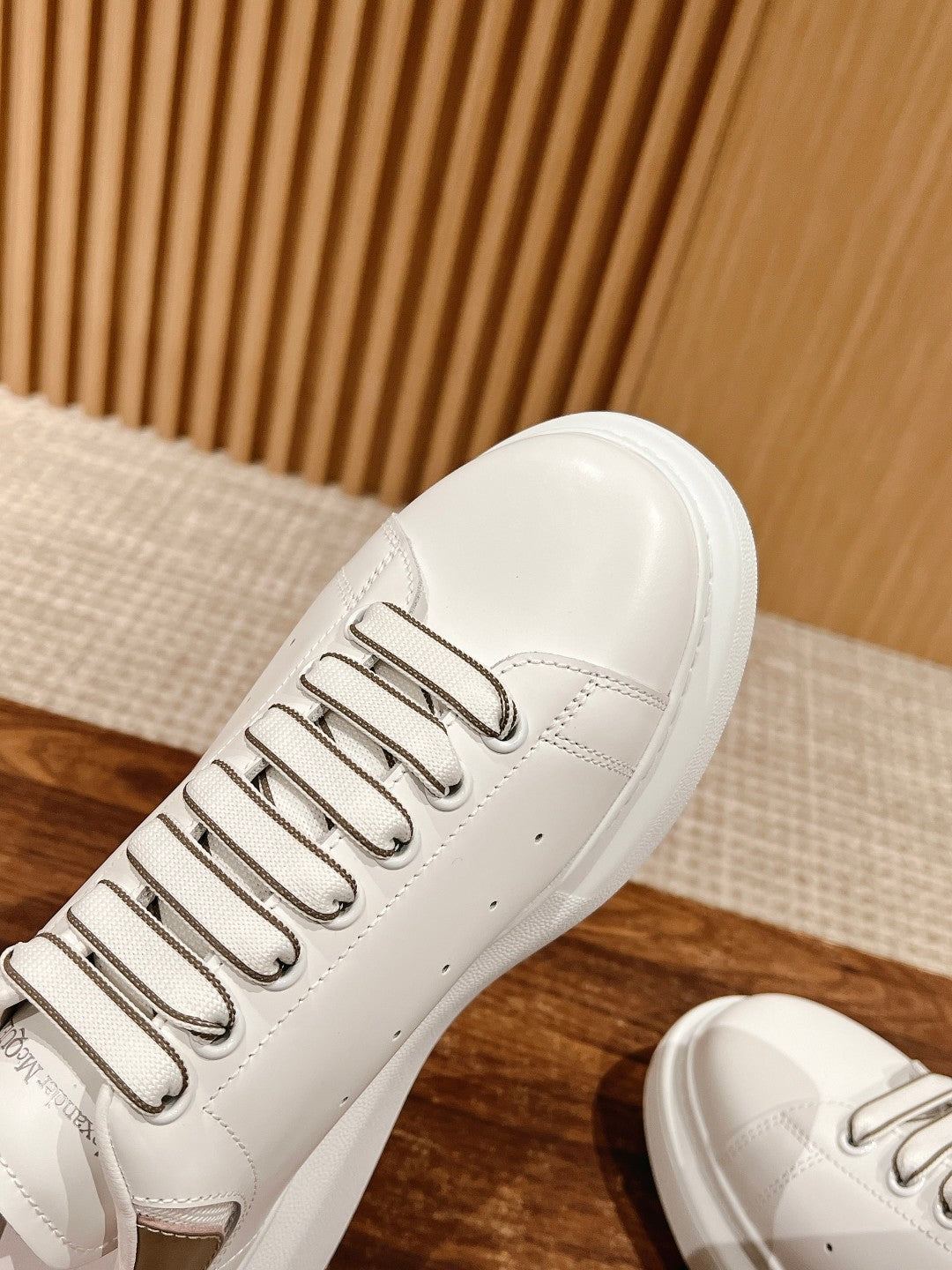 White leather sneaker close-up, showing lace eyelets and side seam stitching