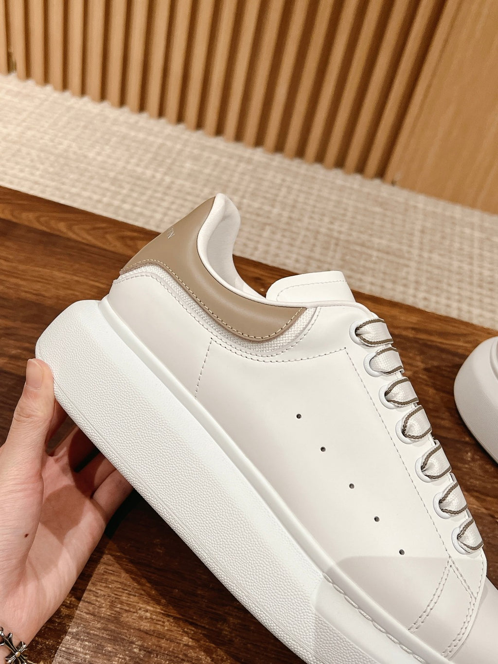 White leather lace-up sneaker with thick rubber sole and clean toe perforations