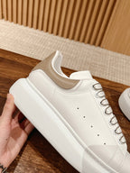 White leather lace-up sneaker with thick rubber sole and clean toe perforations