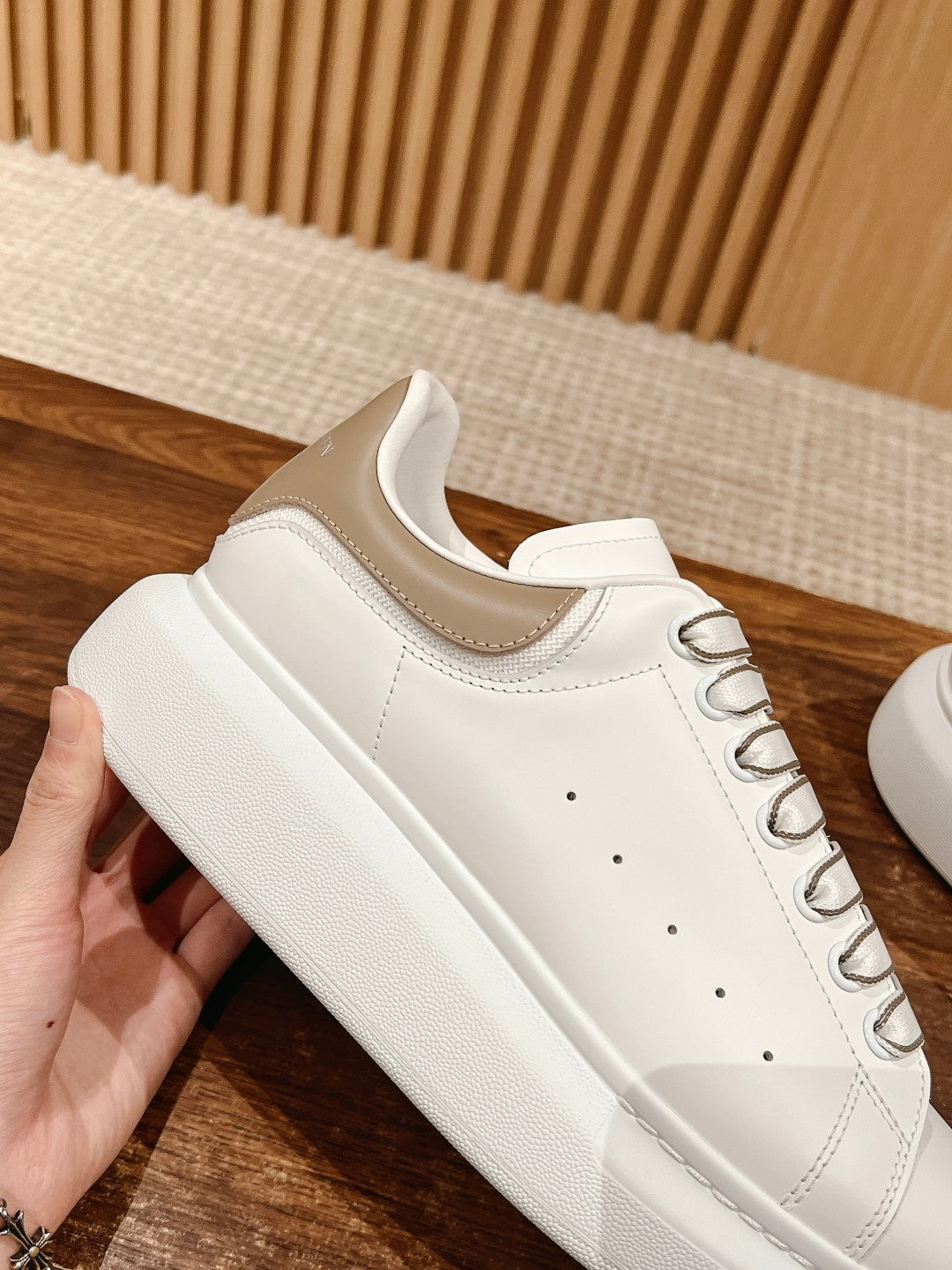 White leather lace-up sneaker with thick rubber sole and clean toe perforations