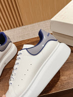 Alexander McQueen sneaker close-up, white upper with blue collar and perforation