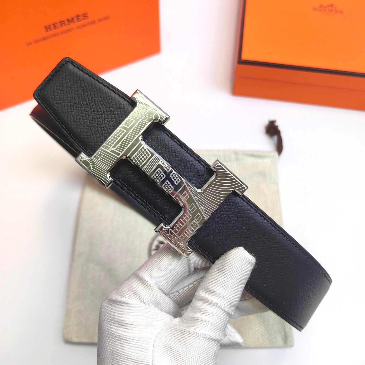 Hermes belt with black leather strap and ornate silver buckle, laid flat
