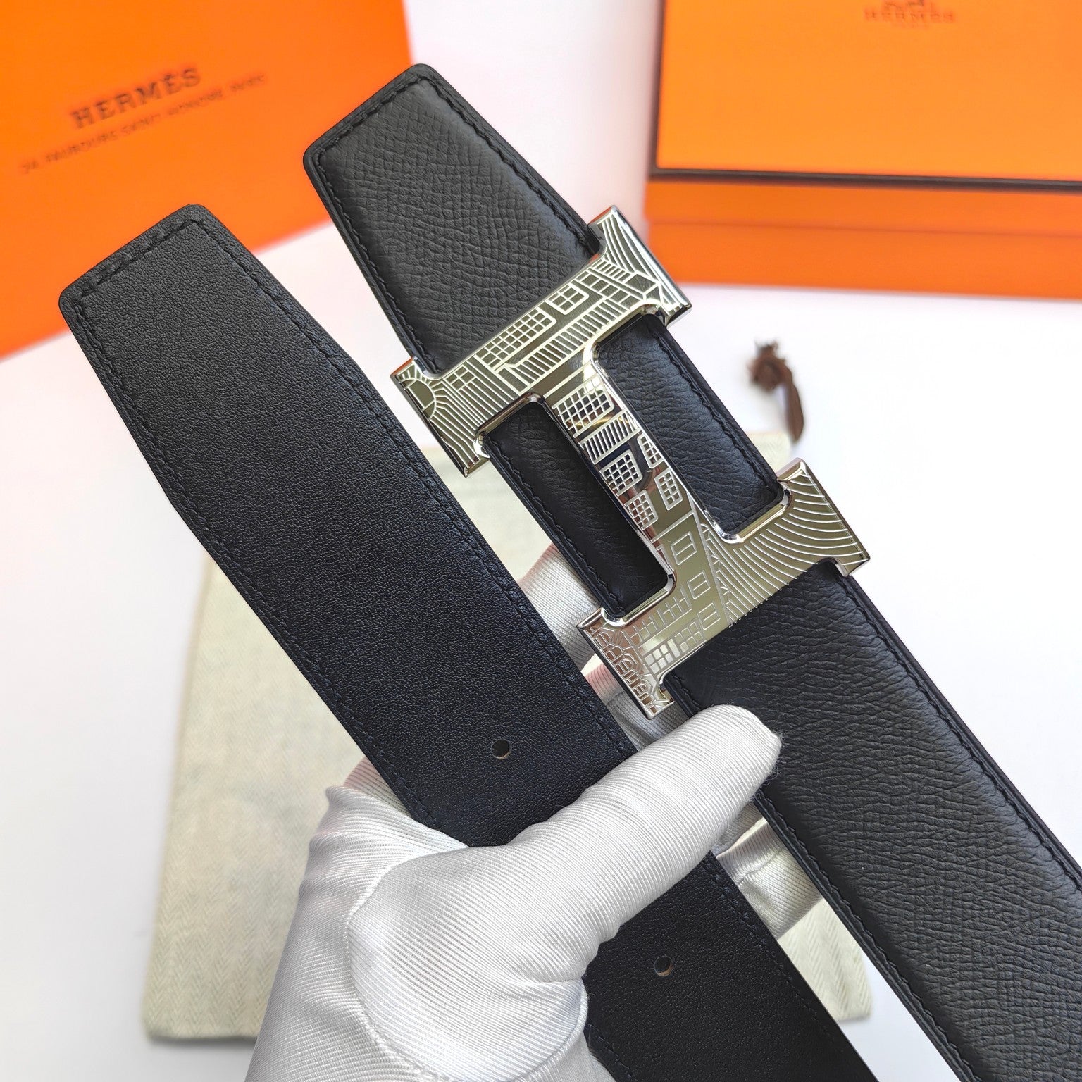 Hermes belt buckle view: black textured strap with silver-tone clasp and holes