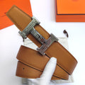 Hermes leather belt with textured tan strap and engraved silver-tone buckle