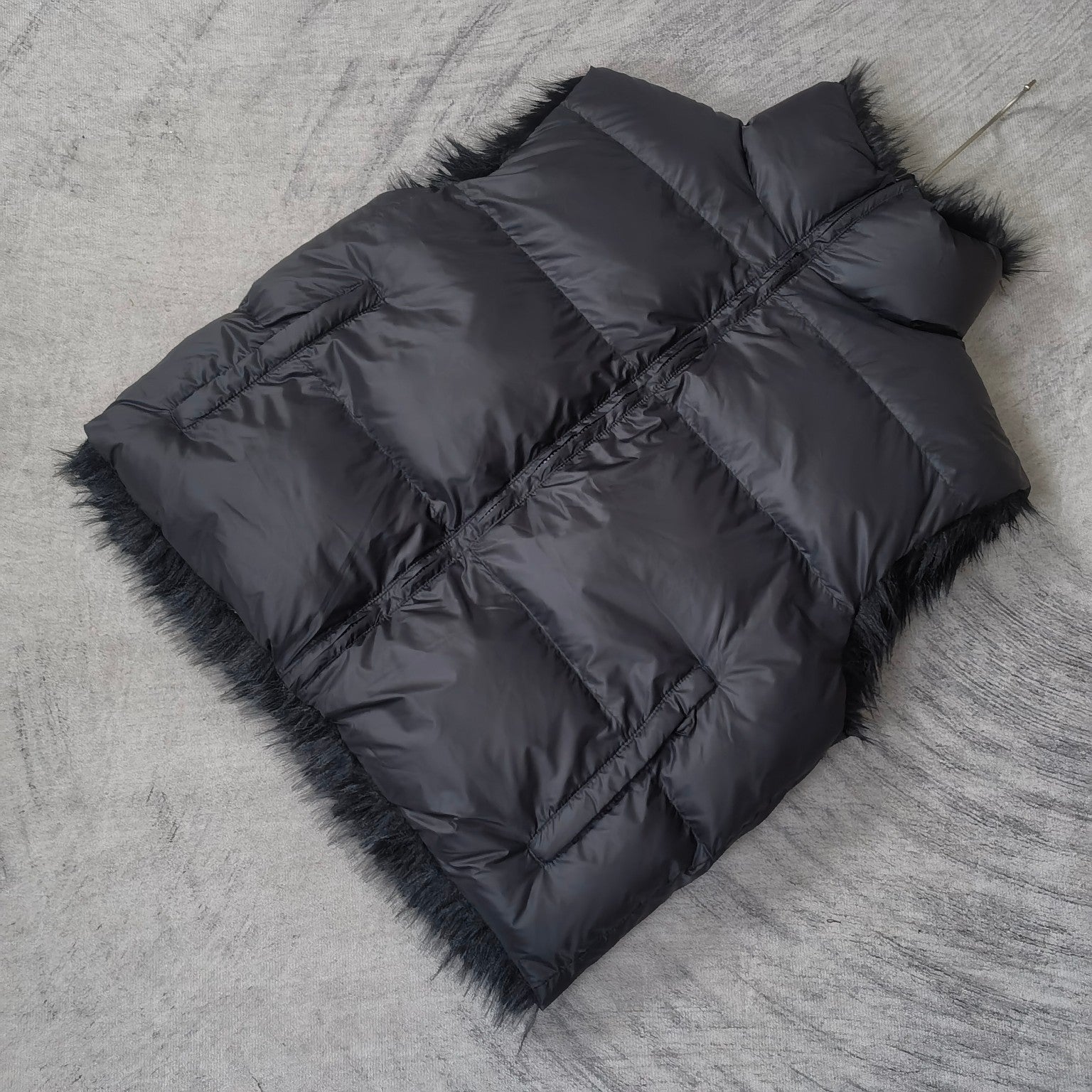 Navy quilted puffer vest laid flat with faux-fur trim and diagonal panel seams