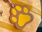 Yellow paw-shaped charm on Louis Vuitton monogram bag with stitched border
