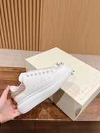 White leather low-top sneakers with lace-up eyelets and thick rubber sole
