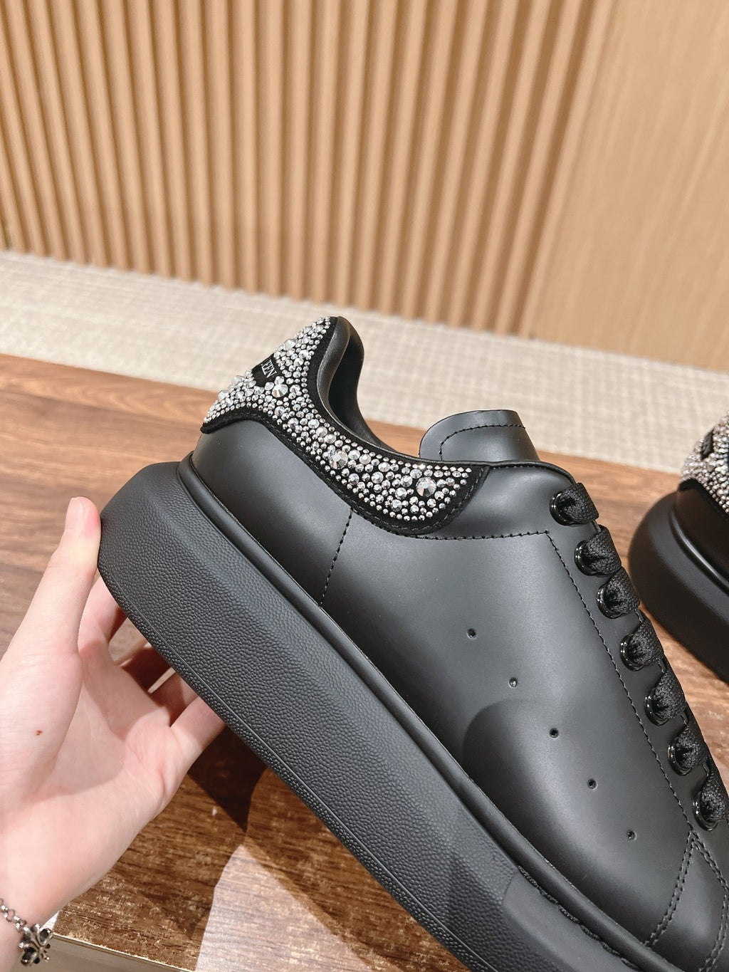 Black lace-up sneaker with rhinestone strap trim around the upper opening